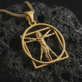 Load image into Gallery viewer, Gold plated Vitruvian Man pendant necklace on textured volcanic rock, premium close-up studio composition emphasizing the Renaissance art design, openwork circle, and symbolic human proportion.

