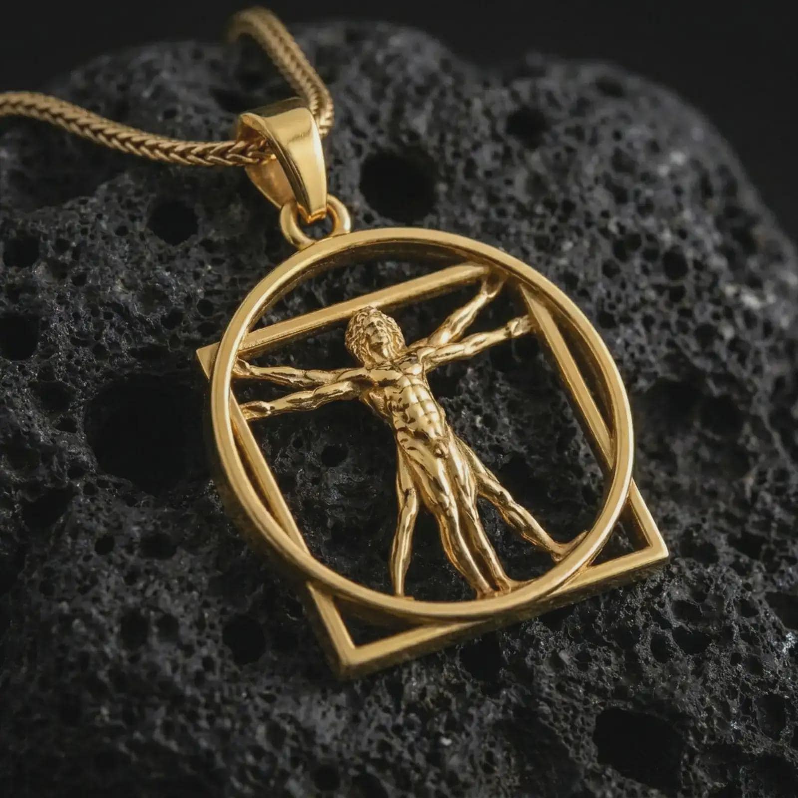 Gold plated Vitruvian Man pendant necklace on textured volcanic rock, premium close-up studio composition emphasizing the Renaissance art design, openwork circle, and symbolic human proportion.