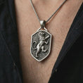 Load image into Gallery viewer, Oxidized heraldic lion shield pendant necklace worn on the chest, close-up lifestyle jewelry photo showing the medieval lion crest on a spiga chain with dark clothing.
