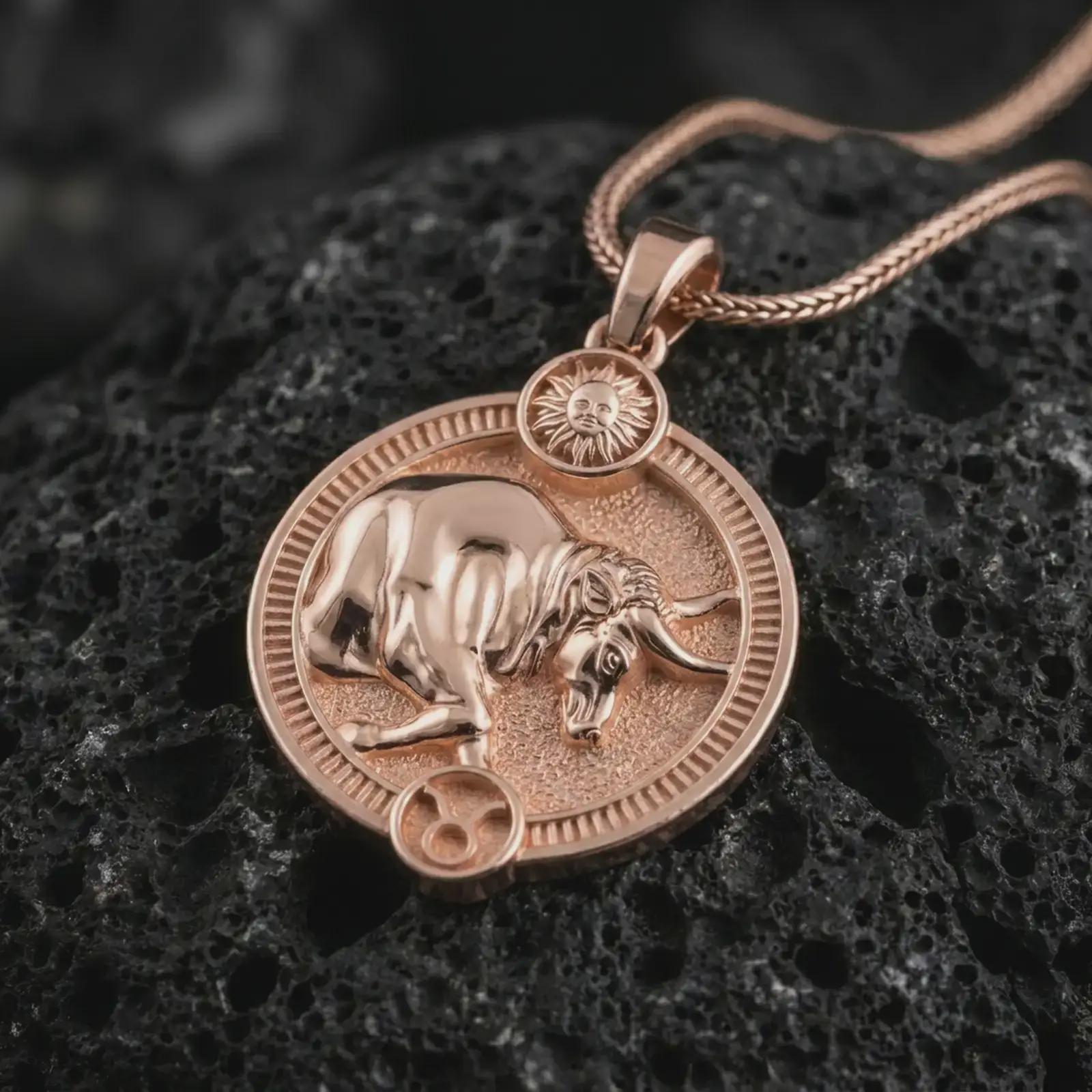 Rose gold plated Taurus zodiac pendant necklace on textured volcanic rock, detailed macro product shot with soft warm reflections and symbolic zodiac styling.
