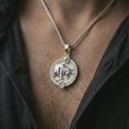 Load image into Gallery viewer, Polished silver Taurus zodiac pendant necklace worn on the chest, masculine lifestyle shot highlighting the bull relief, sun detail, and bright silver finish.

