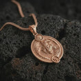 Load image into Gallery viewer, Rose gold plated Capricorn zodiac pendant necklace on textured volcanic rock, detailed macro product shot with soft warm reflections and symbolic zodiac styling.
