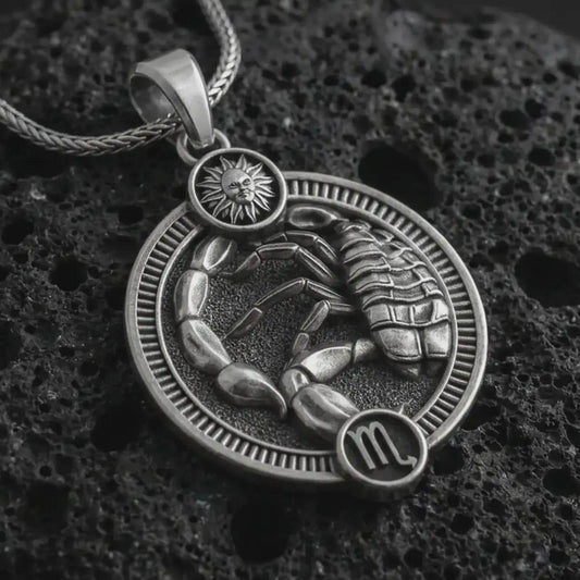 Oxidized Scorpio zodiac pendant necklace on textured volcanic rock, close-up studio shot highlighting the scorpion relief, sun detail, Scorpio symbol, and antique silver contrast.
