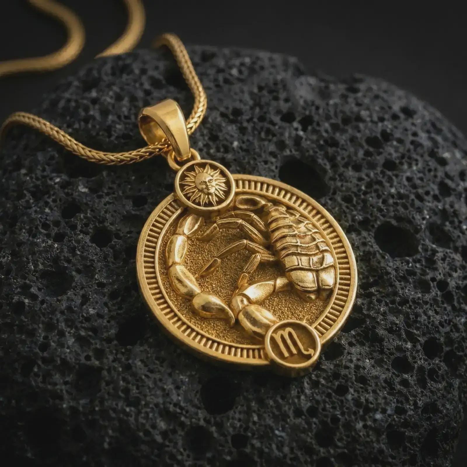 Gold plated Scorpio zodiac pendant necklace on textured volcanic rock, premium close-up studio composition emphasizing the scorpion figure, segmented tail, and astrology medallion design.