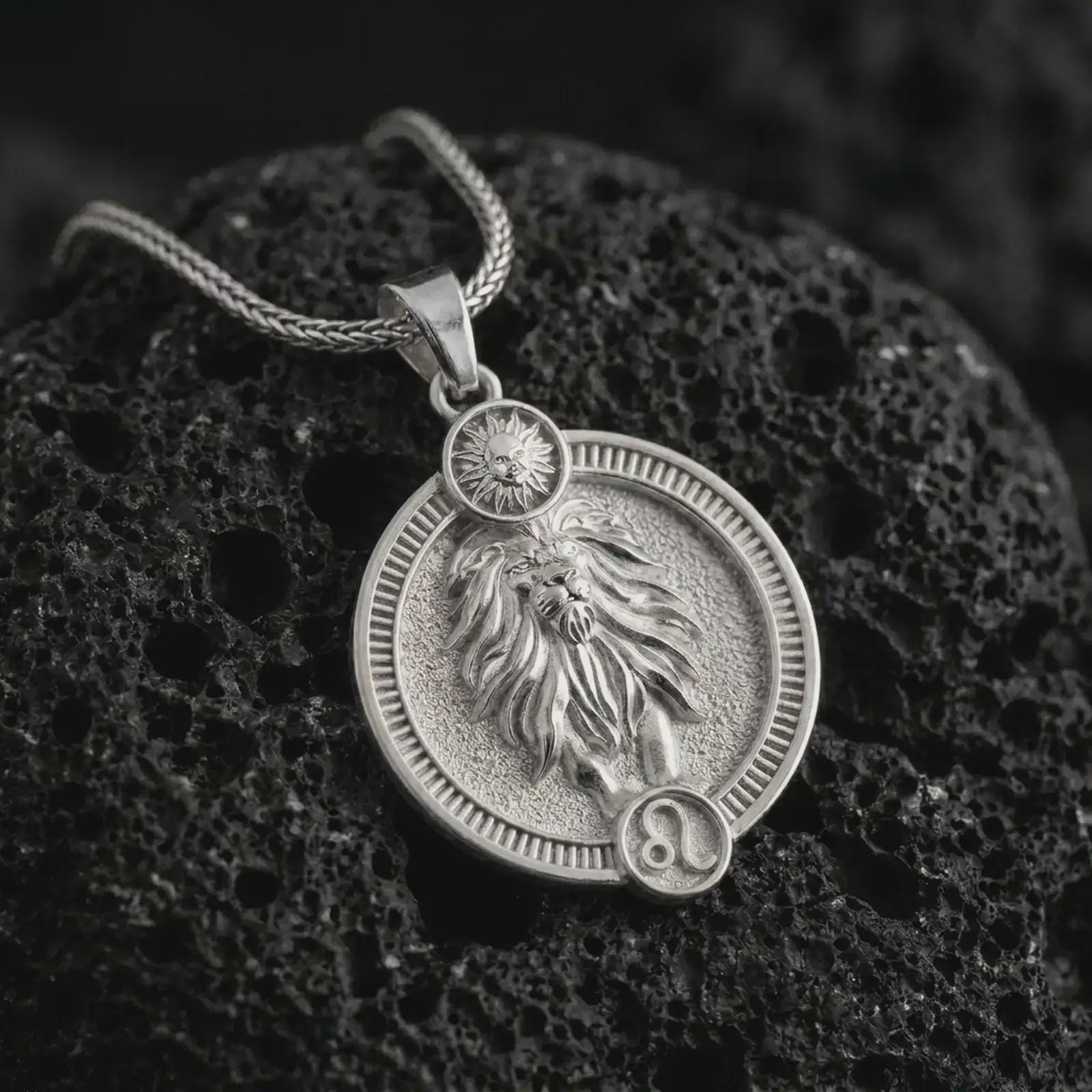 Polished silver Leo zodiac pendant necklace on textured volcanic rock, centered macro jewelry photo with detailed lion horoscope relief and bright silver highlights.