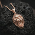 Load image into Gallery viewer, A rose gold plated gorilla pendant is photographed on porous volcanic rock in a close-up studio composition with refined luxury lighting and sculpted fur detail.
