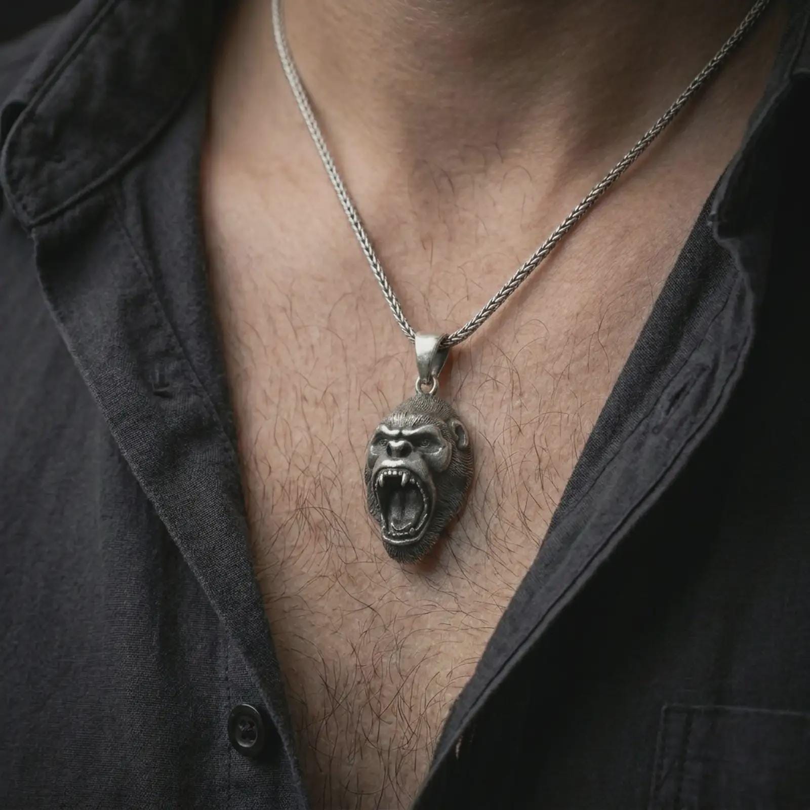 An oxidized gorilla pendant is worn on the neck in a close-up lifestyle shot, centered on the chest as a bold masculine animal amulet.