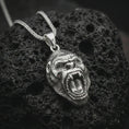 Load image into Gallery viewer, A polished silver gorilla pendant is displayed on black volcanic rock in a premium macro studio close-up with sharp facial detail and bold animal character.
