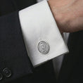 Load image into Gallery viewer, A polished silver Our Lady of Guadalupe cufflink is worn on a shirt cuff in a premium close-up lifestyle image, showing the sacred Virgin Mary relief clearly.
