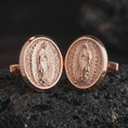 Load image into Gallery viewer, Rose gold plated Our Lady of Guadalupe cufflinks are photographed on porous volcanic rock in a close-up studio composition with refined luxury lighting and religious detail.
