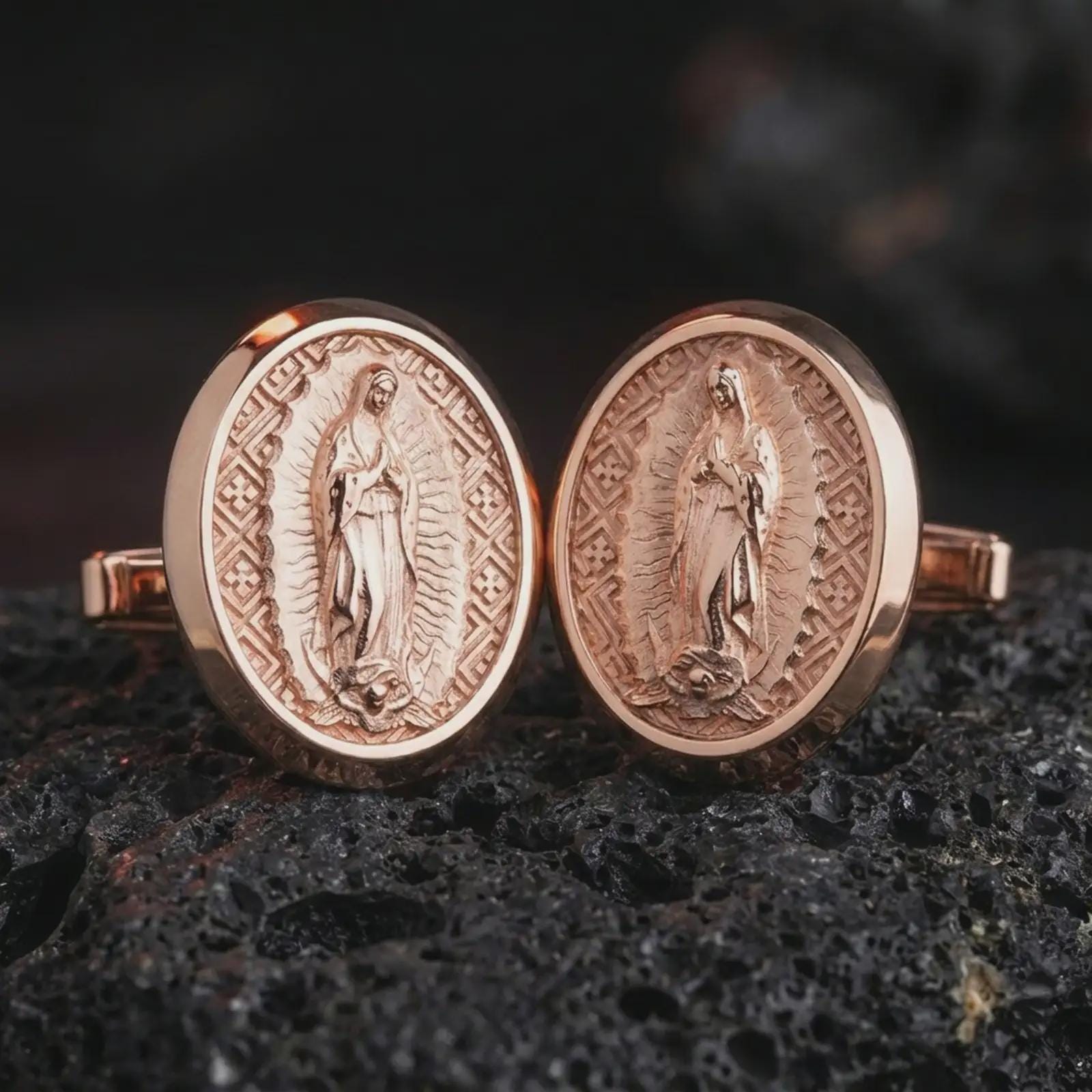 Rose gold plated Our Lady of Guadalupe cufflinks are photographed on porous volcanic rock in a close-up studio composition with refined luxury lighting and religious detail.