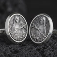 Load image into Gallery viewer, An oxidized Mary Magdalene cufflink pair rests on dark volcanic rock in a macro studio close-up, showing a detailed saint relief inside oval frames.
