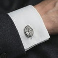 Load image into Gallery viewer, An oxidized St Dominic cufflink is worn on a white shirt cuff in a close-up lifestyle shot, styled with a dark suit as a meaningful Catholic accessory.
