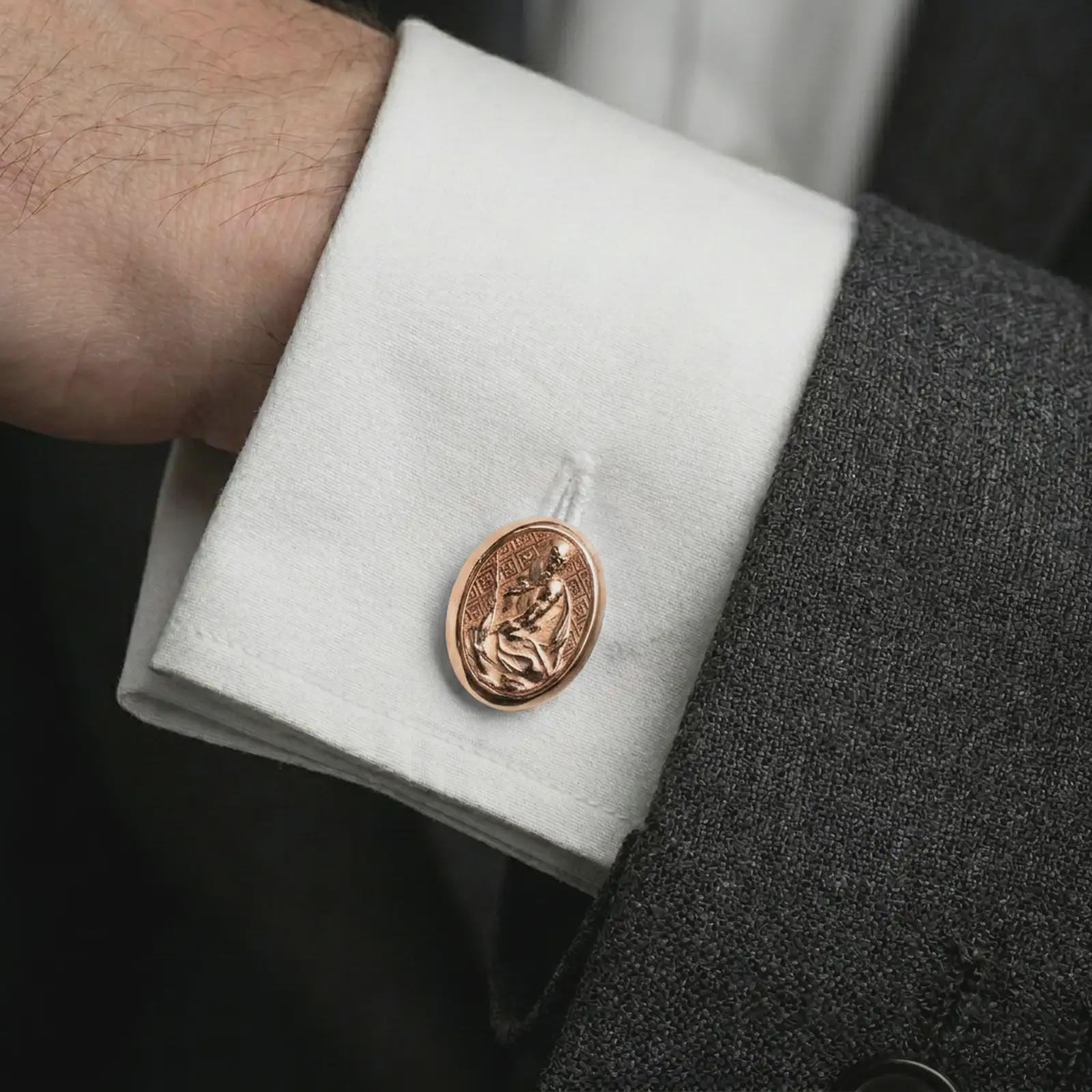 A rose gold plated Pensive Christ cufflink is worn on a shirt cuff in a close-up lifestyle composition, highlighting its oval frame and sacred Christ design.