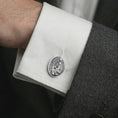 Load image into Gallery viewer, A polished silver Pensive Christ cufflink is worn on a shirt cuff in a premium close-up lifestyle image, showing the seated Jesus relief clearly.

