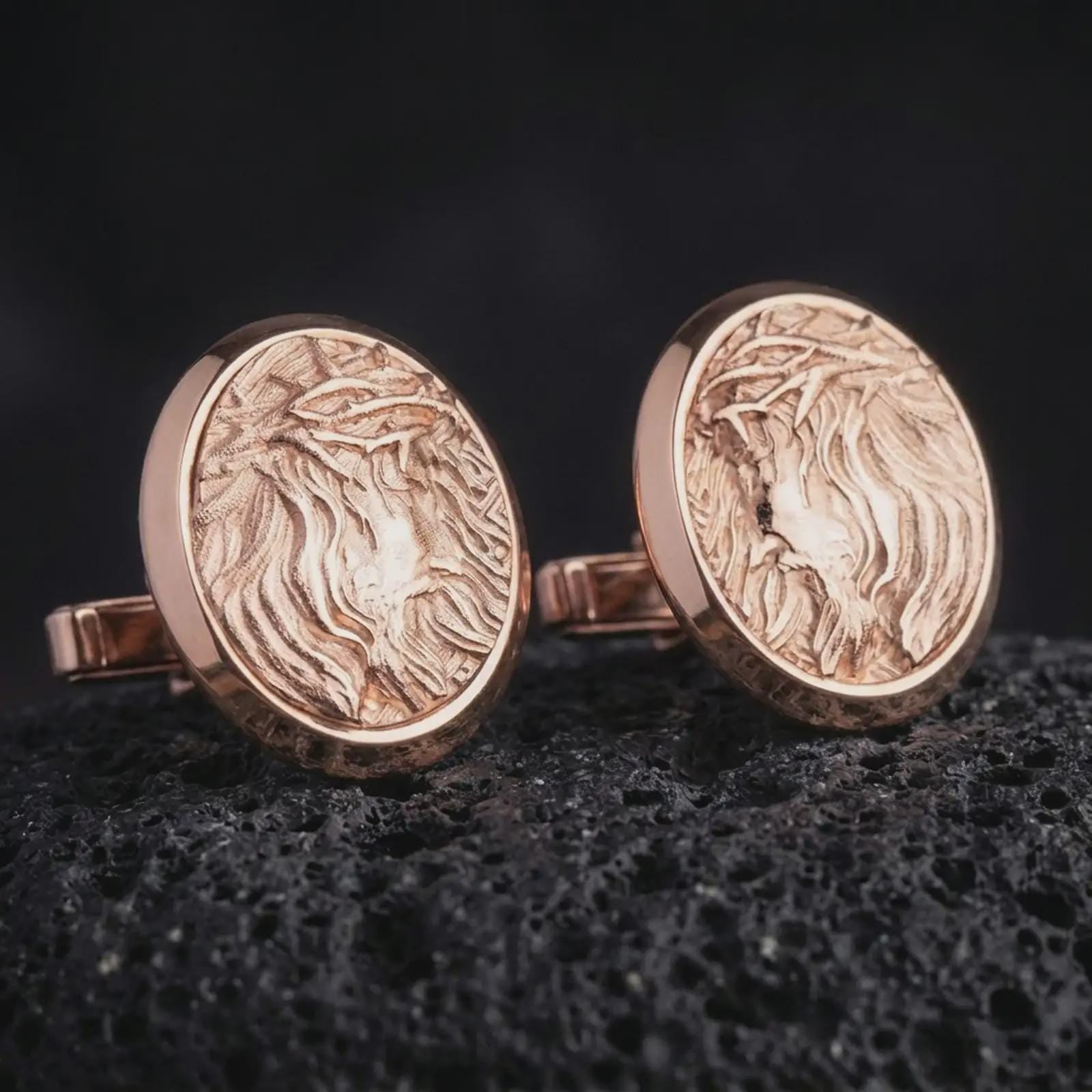 Rose gold plated Jesus Crown of Thorns cufflinks are photographed on porous volcanic rock in a close-up studio composition with refined luxury lighting and religious detail.