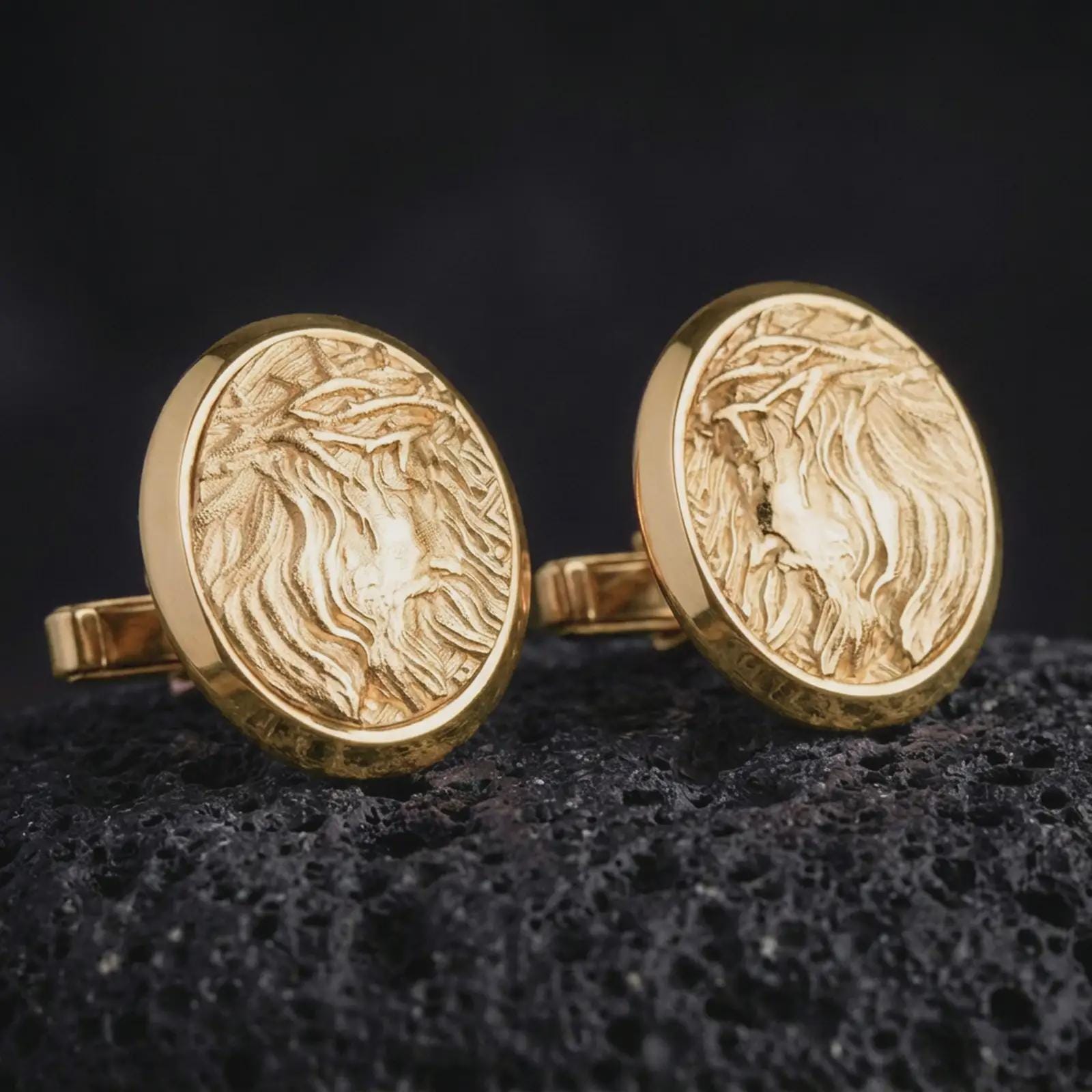 Gold plated Jesus Crown of Thorns cufflinks sit on textured volcanic rock in a dramatic studio macro shot, highlighting the sacred Christ medallion design.