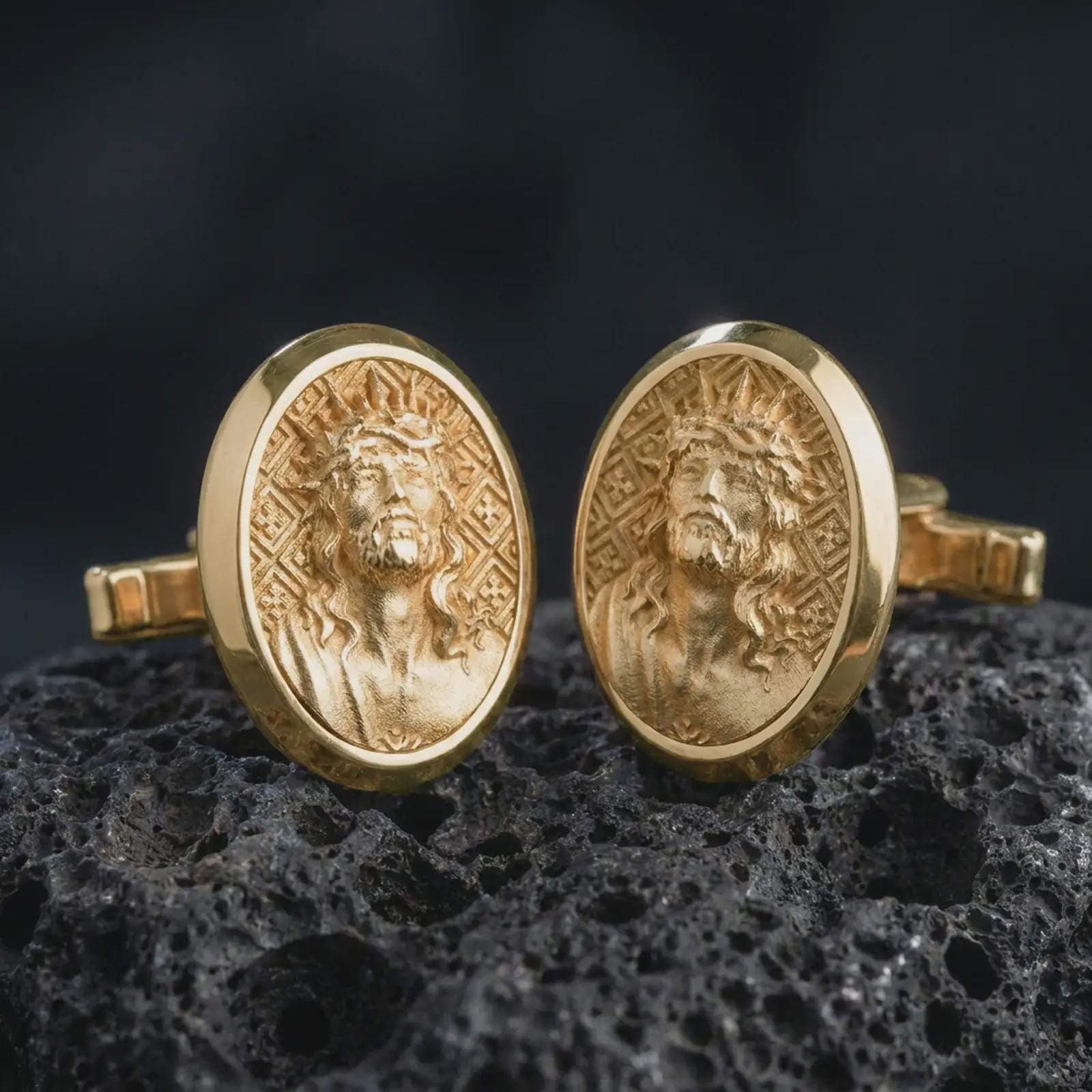 Gold plated Jesus Crown of Thorns cufflinks sit on textured volcanic rock in a dramatic studio macro shot, highlighting the sacred Christ portrait design.