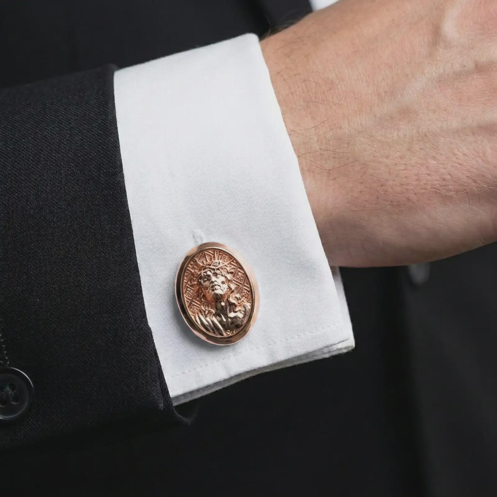 A rose gold plated Jesus Crown of Thorns cufflink is worn on a shirt cuff in a close-up lifestyle composition, highlighting its oval frame and sacred Jesus design.