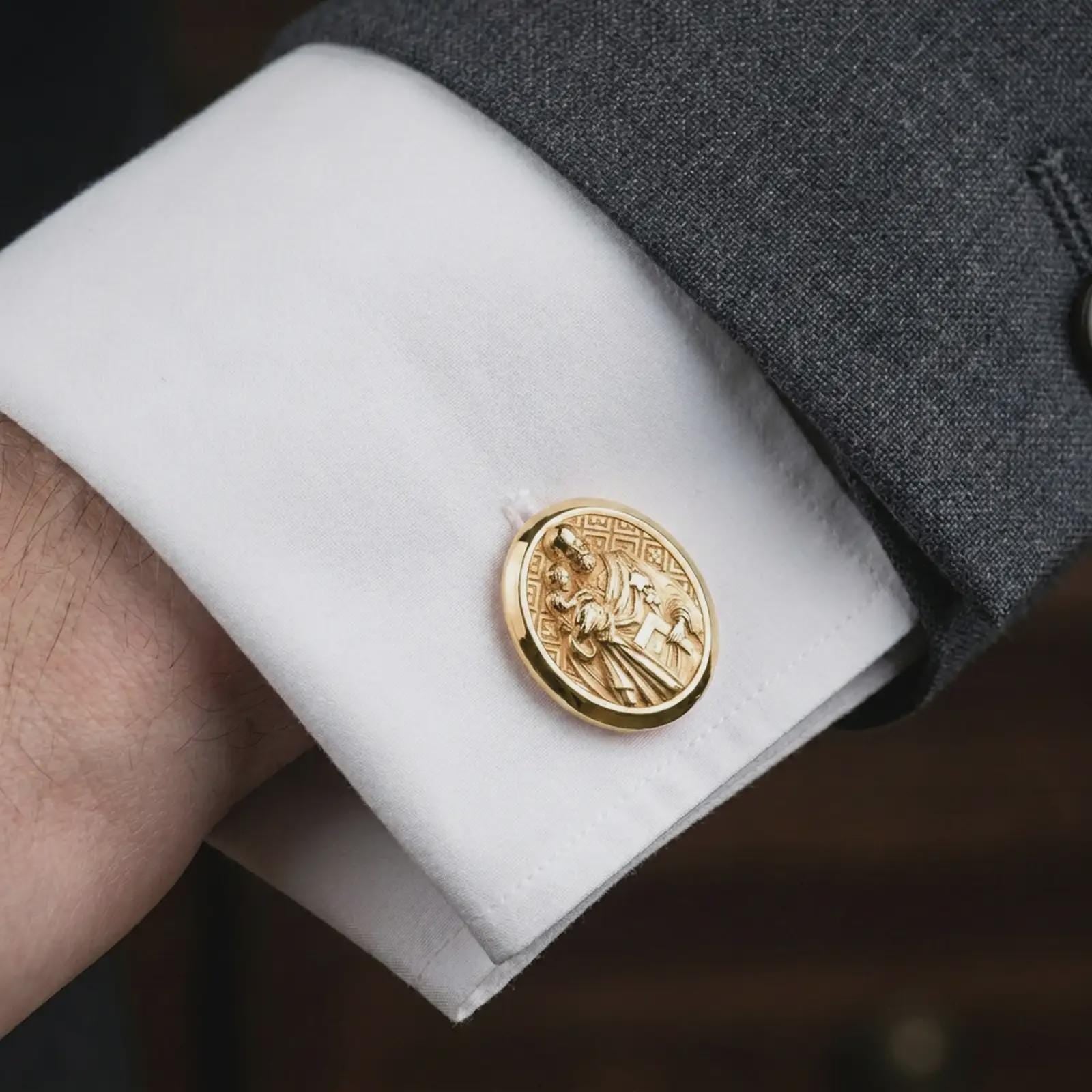 Gold plated Saint Joseph cufflinks worn on a crisp white cuff with a tailored suit in a premium lifestyle composition, presenting a meaningful Christian accessory for men.