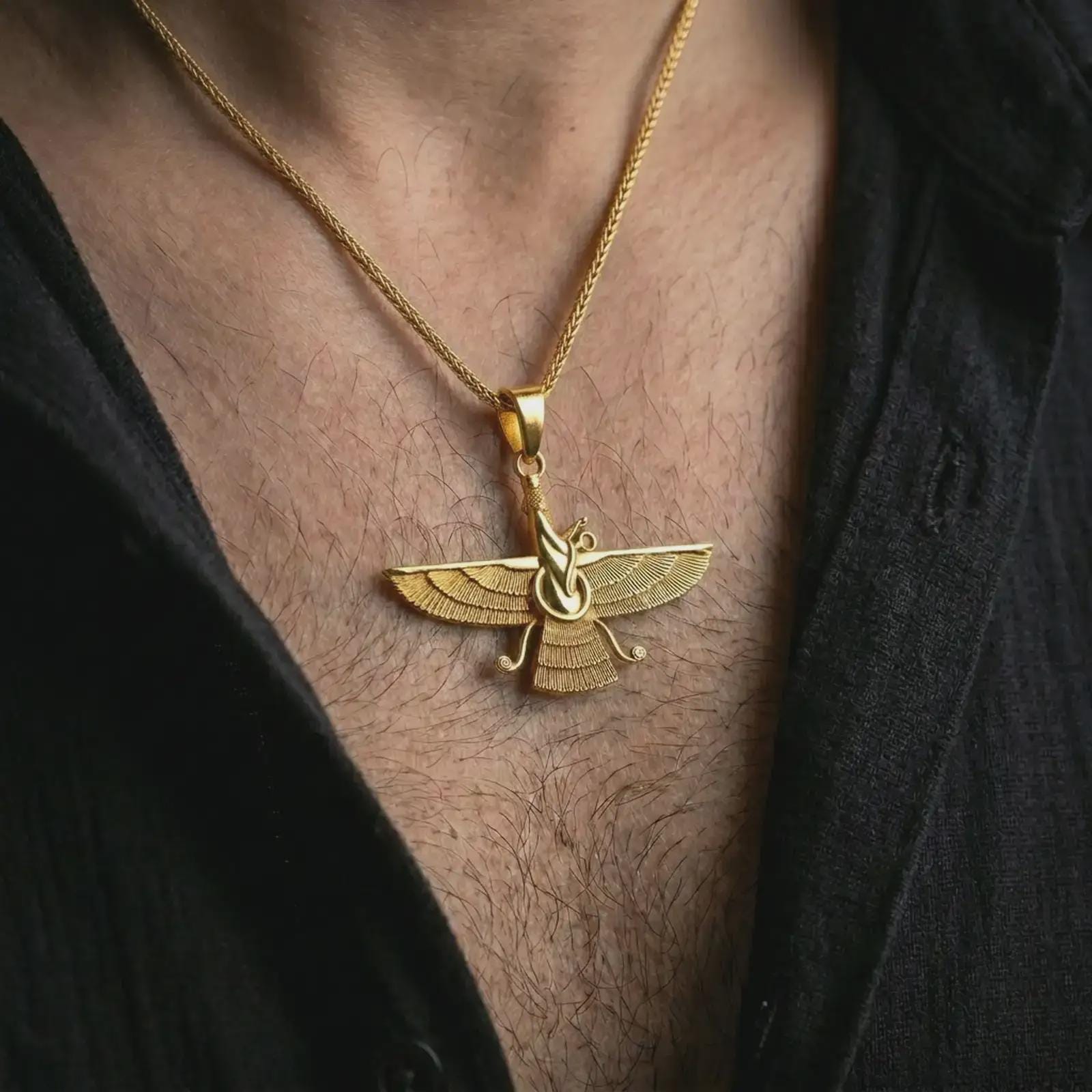 Gold plated Faravahar pendant necklace worn on the chest, premium lifestyle jewelry photo with the Zoroastrian winged pendant centered on a spiga chain.