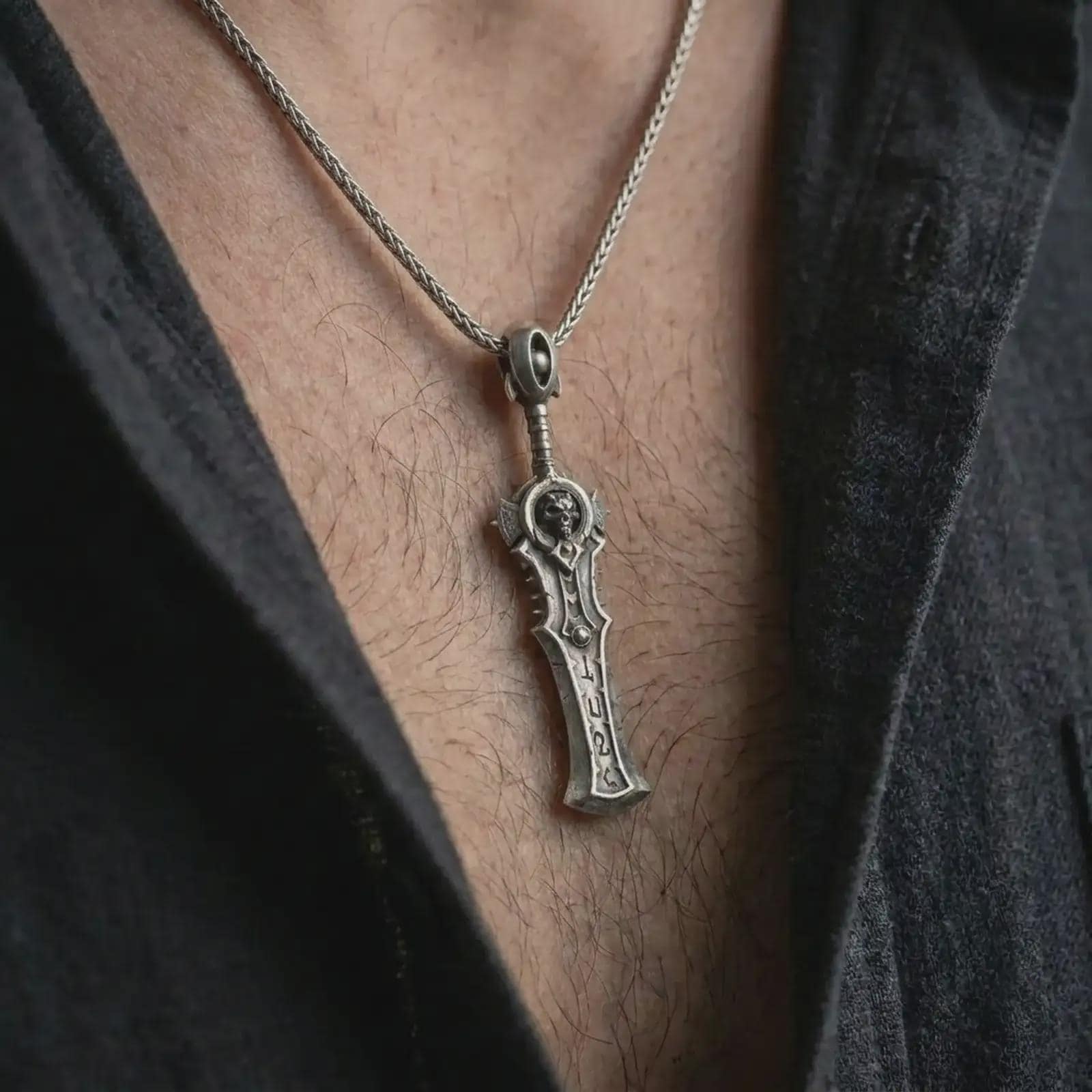 An oxidized demon slayer sword pendant is worn on the neck in a close-up lifestyle shot, centered on the chest as a dark fantasy warrior necklace.