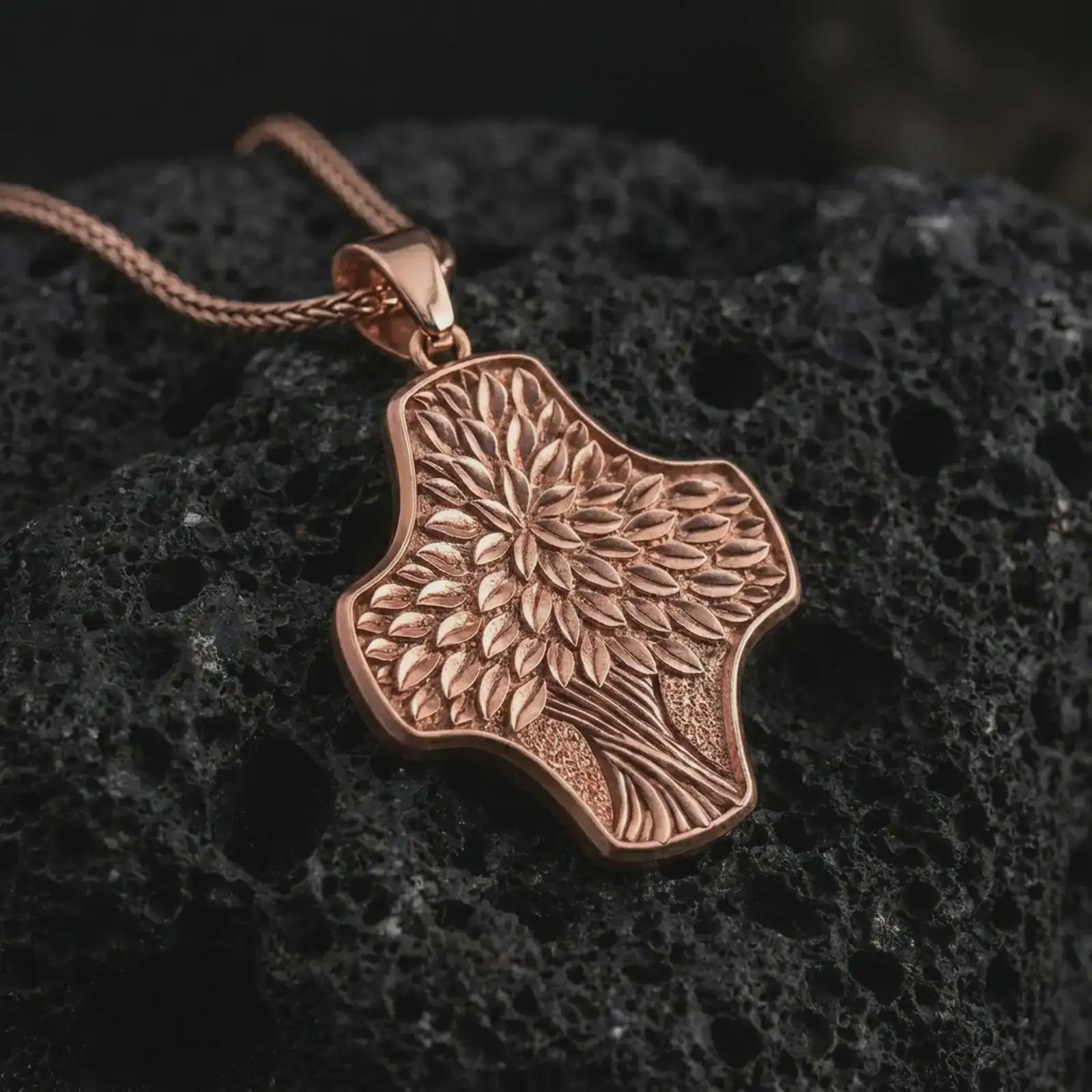 A rose gold plated Tree of Life cross pendant is photographed on porous volcanic rock in a close-up studio composition with refined luxury lighting and botanical detail.