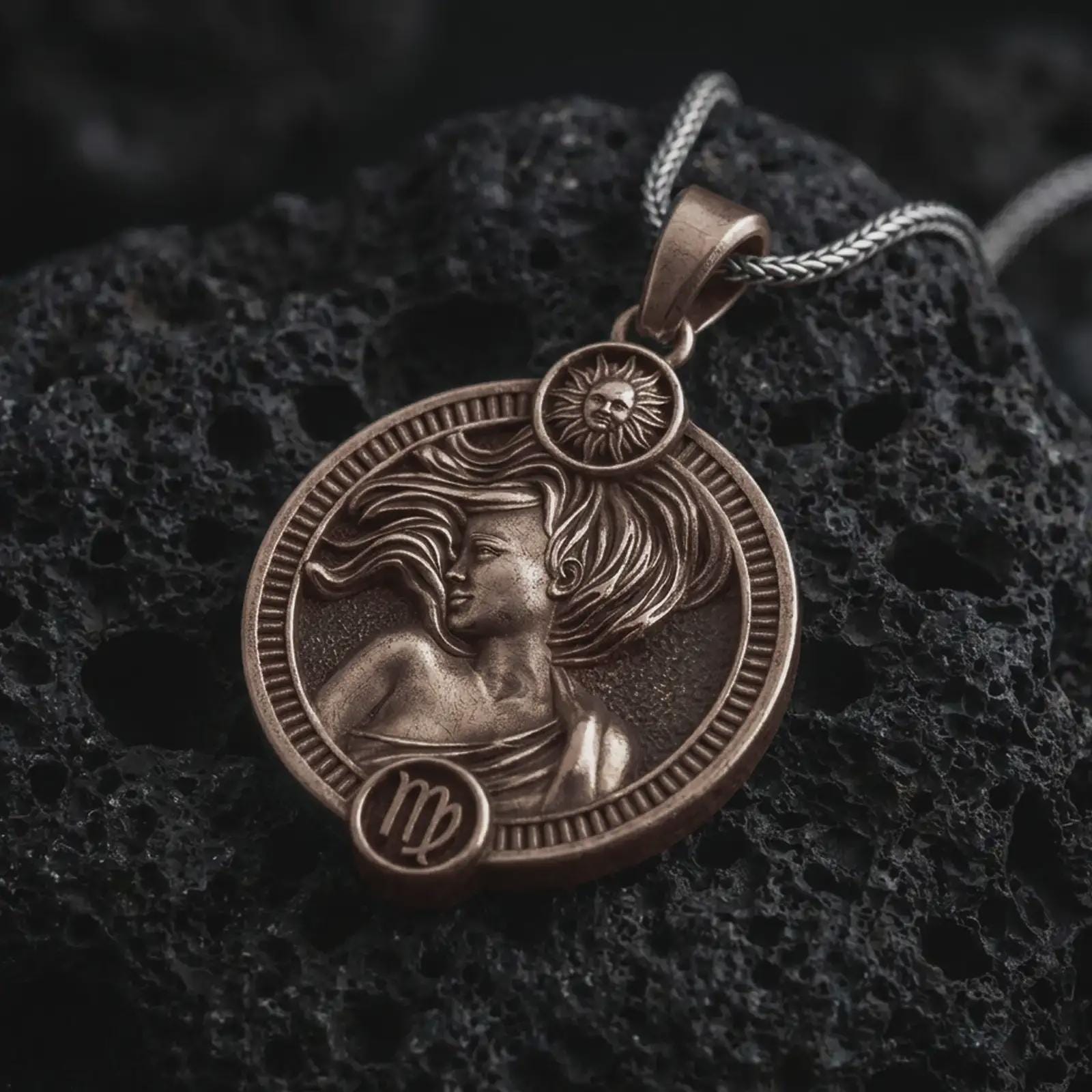 Bronze Virgo zodiac pendant necklace on textured volcanic rock, close-up studio shot highlighting the elegant woman relief, flowing hair, sun detail, and antique silver contrast.