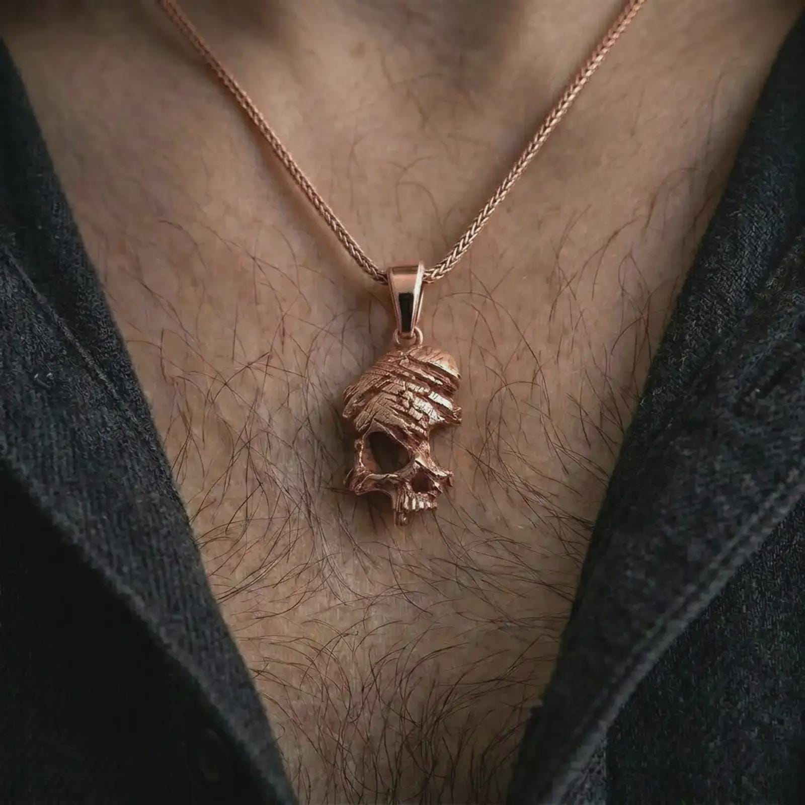 Rose gold plated cracked skull pendant necklace worn on the chest, close-up lifestyle shot featuring the dark cracked skull design with warm rose gold tones.