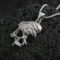 Load image into Gallery viewer, Polished silver cracked skull pendant necklace on textured volcanic rock, centered macro jewelry photo with detailed bone structure, broken surface effect, and bright silver highlights.
