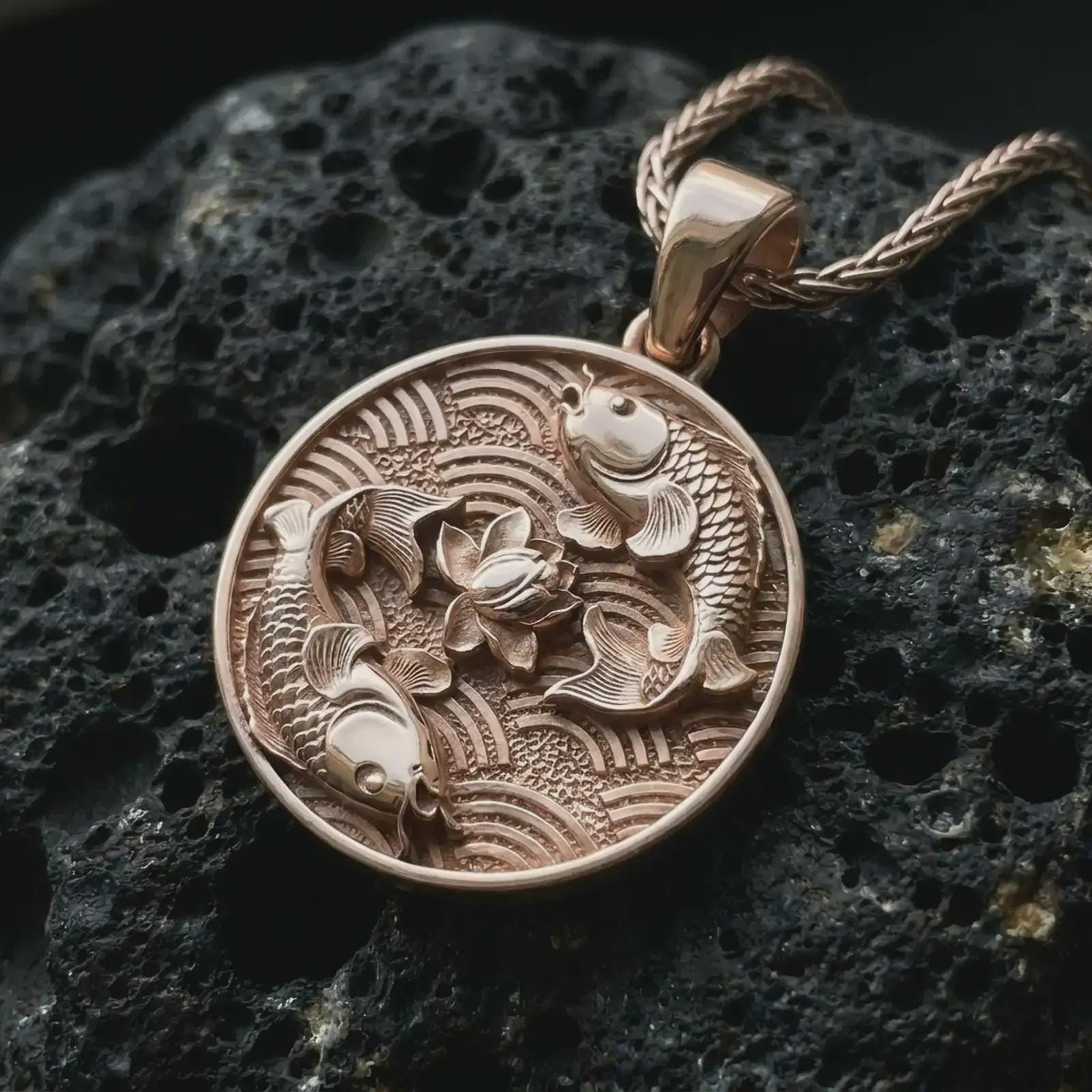 Rose gold plated koi fish lotus pendant necklace on textured volcanic rock, detailed macro product shot with soft warm reflections and symbolic koi fish styling.