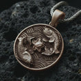 Load image into Gallery viewer, Bronze koi fish lotus pendant necklace on textured volcanic rock, close-up studio shot highlighting the twin koi relief, lotus flower center, wave pattern, and antique silver contrast.
