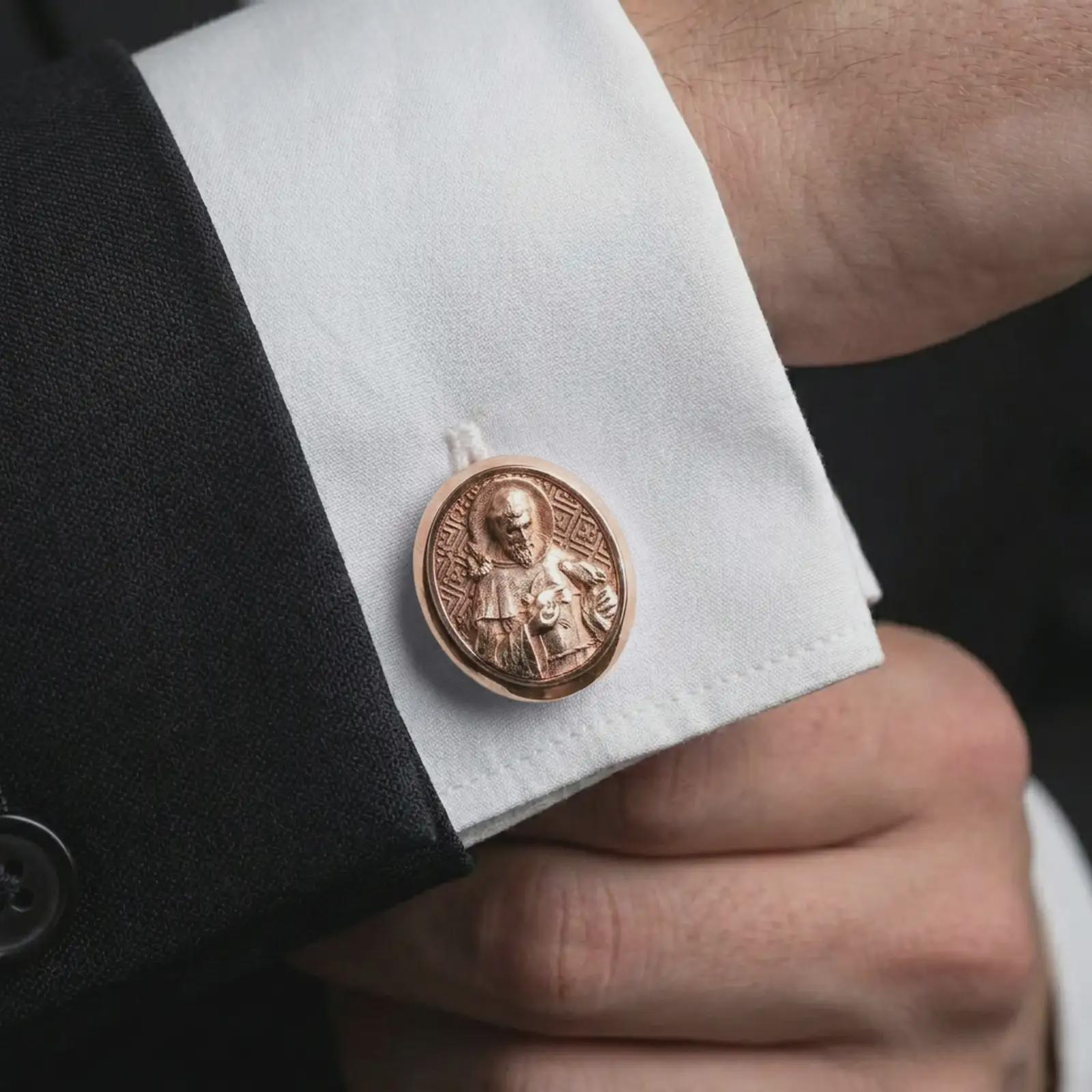 A rose gold plated Saint Francis cufflink is worn on a shirt cuff in a close-up lifestyle composition, highlighting its oval frame and Saint Francis design.