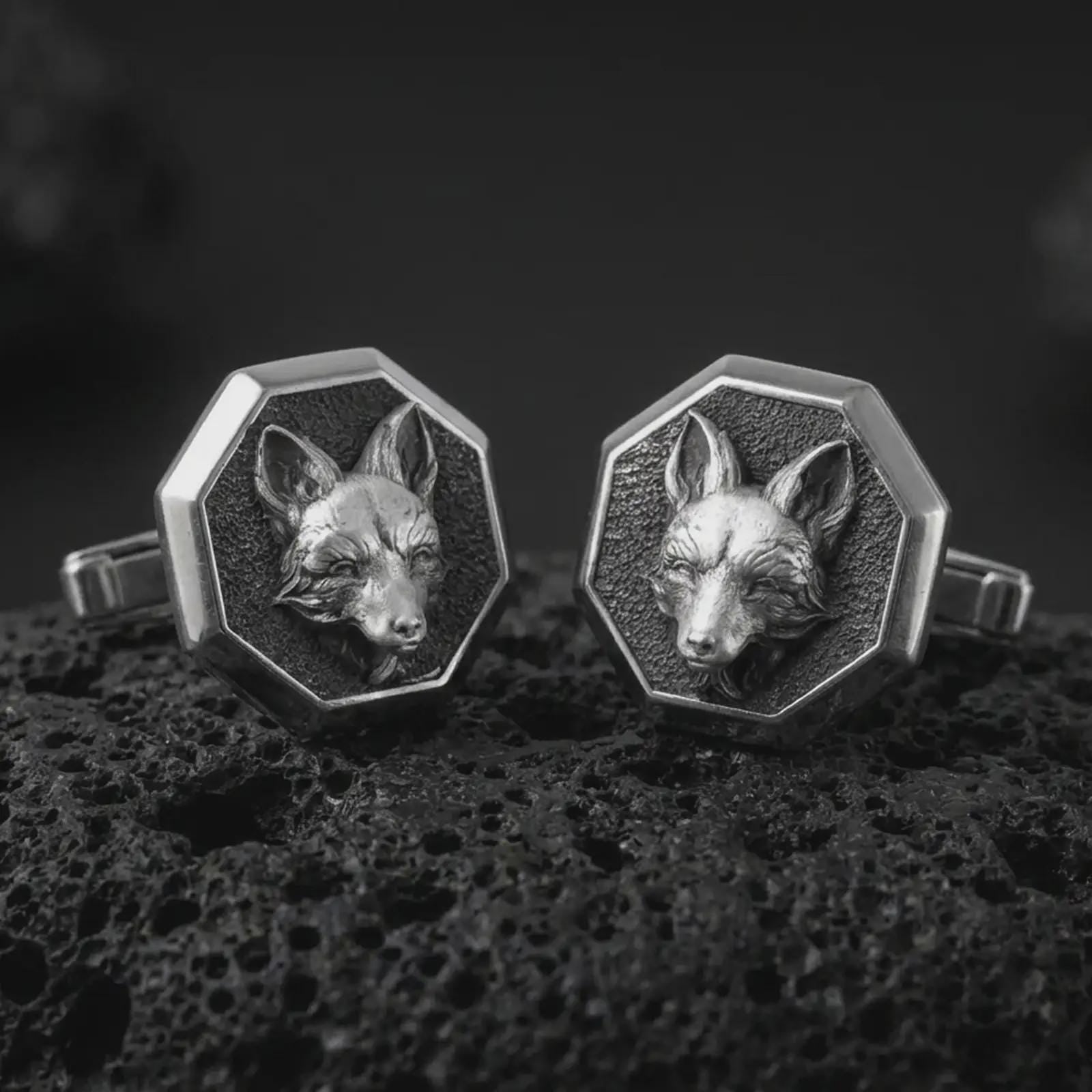An oxidized fox head cufflink pair rests on dark volcanic rock in a macro studio close-up, showing sculpted woodland animal detail inside octagon frames.