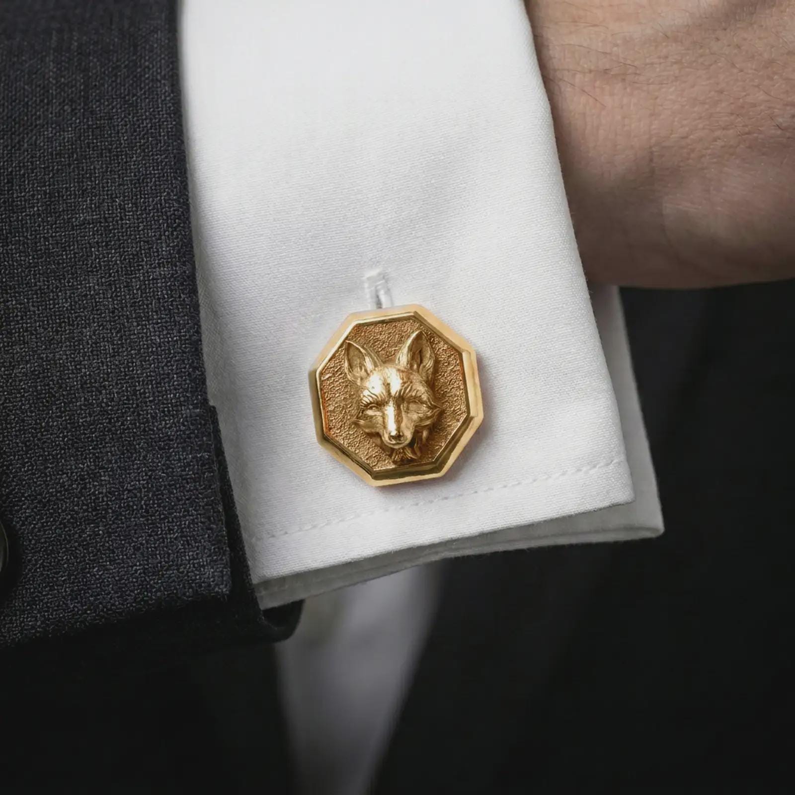 A gold plated fox head cufflink is worn on a white cuff in a close-up lifestyle shot, styled as a meaningful groomsmen accessory for men.