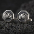 Load image into Gallery viewer, An oxidized lioness head cufflink pair rests on dark volcanic rock in a macro studio close-up, showing a sculpted wild cat profile inside octagon frames.
