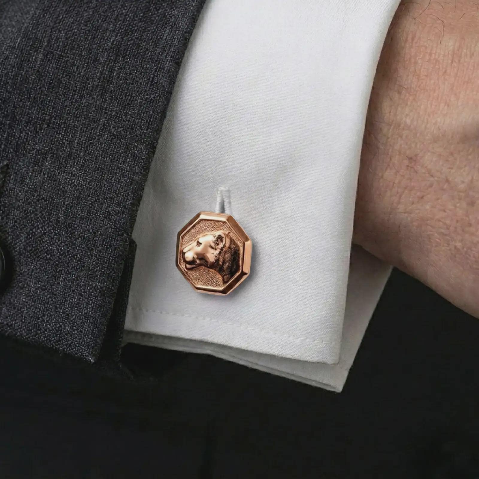 A rose gold plated lioness head cufflink is worn on a shirt cuff in a close-up lifestyle composition, highlighting its octagon frame and sculpted lioness design.