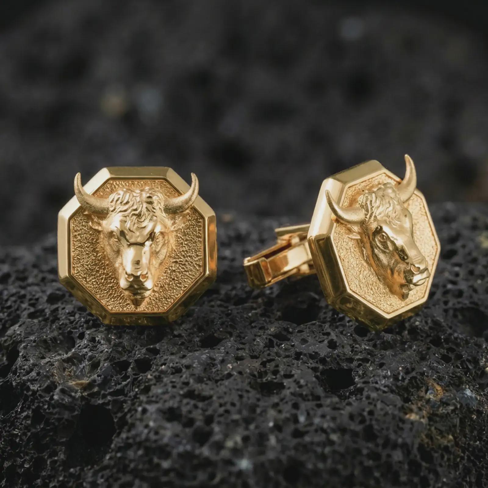 Gold plated bull head cufflinks sit on textured volcanic rock in a dramatic studio macro shot, highlighting the Taurus-inspired animal motif and formal accessory design.