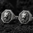 Load image into Gallery viewer, An oxidized lion head cufflink pair rests on dark volcanic rock in a macro studio close-up, showing a fierce roaring big cat with a sculpted mane inside octagon frames.
