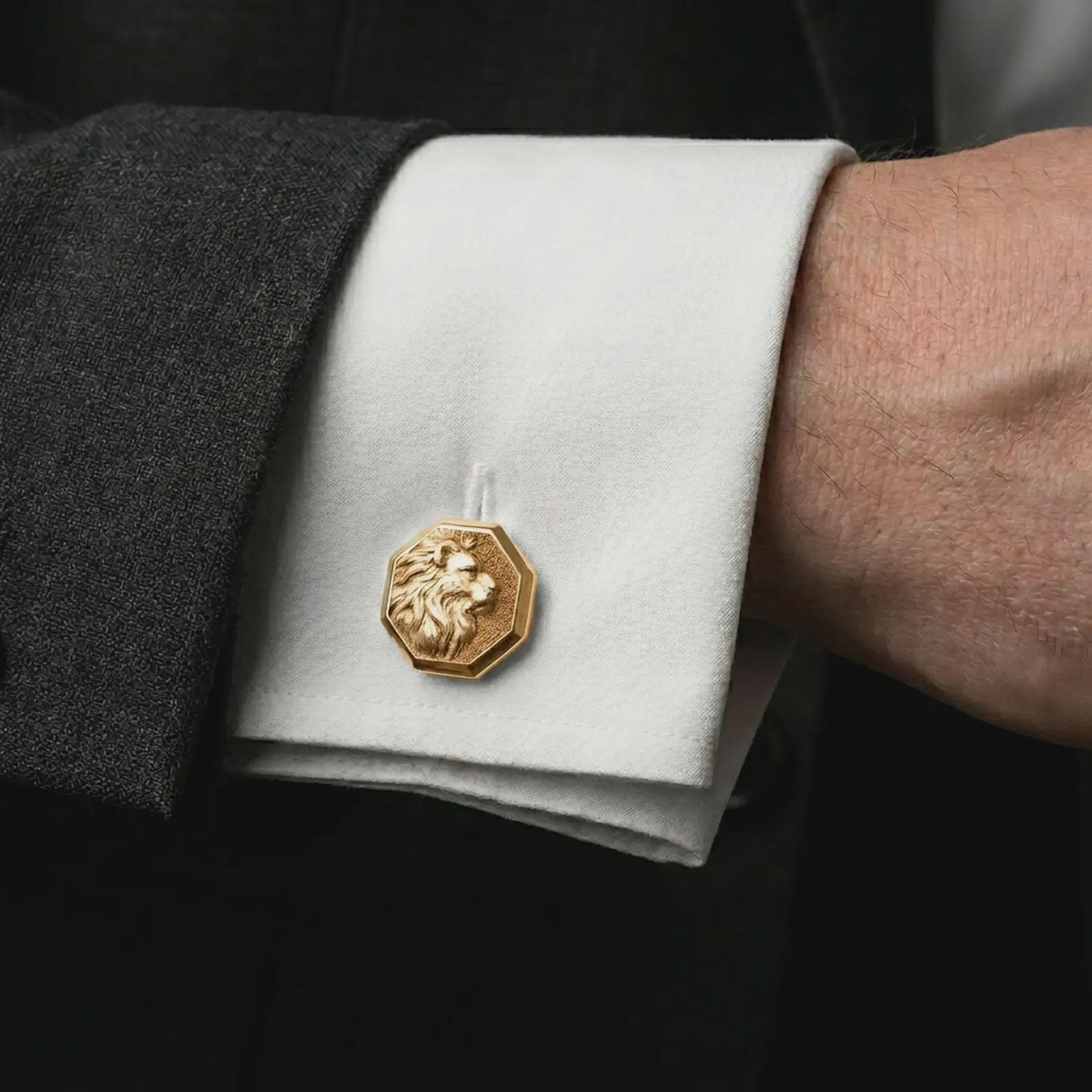 A gold plated lion profile cufflink is worn on a white cuff in a close-up lifestyle shot, styled as a meaningful groomsmen accessory for men.