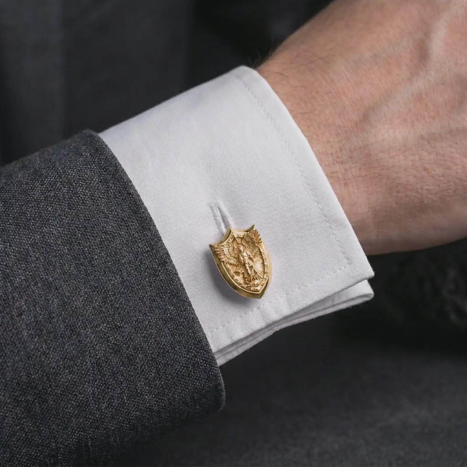 A gold plated Saint Michael cufflink is worn on a white cuff in a close-up lifestyle shot, styled as a thoughtful protection gift for Catholic men.