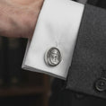 Load image into Gallery viewer, An oxidized Virgin Mary cufflink is worn on a white shirt cuff in a close-up lifestyle shot, styled with a dark suit as a meaningful Catholic accessory.
