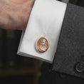Load image into Gallery viewer, A rose gold plated Virgin Mary cufflink is worn on a shirt cuff in a close-up lifestyle composition, highlighting its oval frame and sacred Virgin Mary design.
