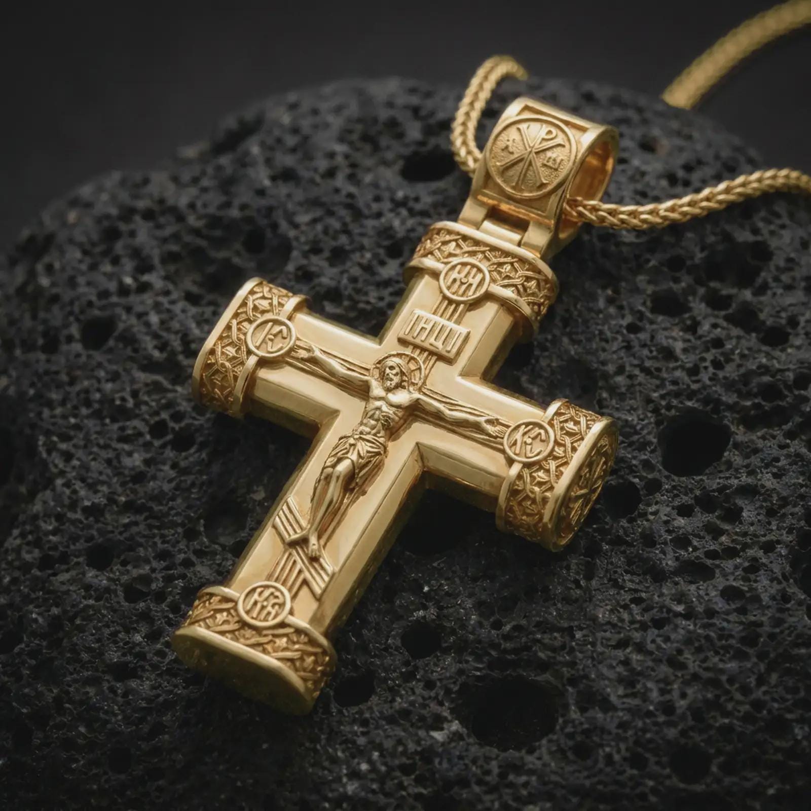 Gold plated crucifix cross pendant necklace on textured volcanic rock, premium close-up studio composition emphasizing the sacred cross shape, religious details, and bold Christian medallion design.