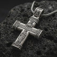 Load image into Gallery viewer, Oxidized crucifix cross pendant necklace on textured volcanic rock, close-up studio shot highlighting the Jesus figure, INRI plaque, ornate barrel ends, and antique silver contrast.
