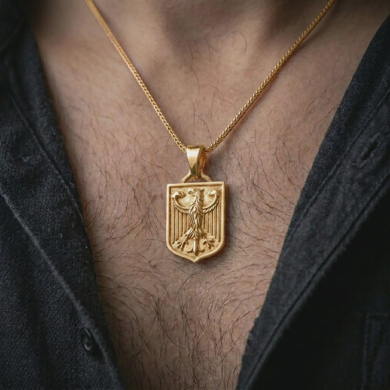 Gold plated German eagle shield pendant necklace worn on the chest, premium lifestyle jewelry photo with the eagle shield pendant centered on a spiga chain.