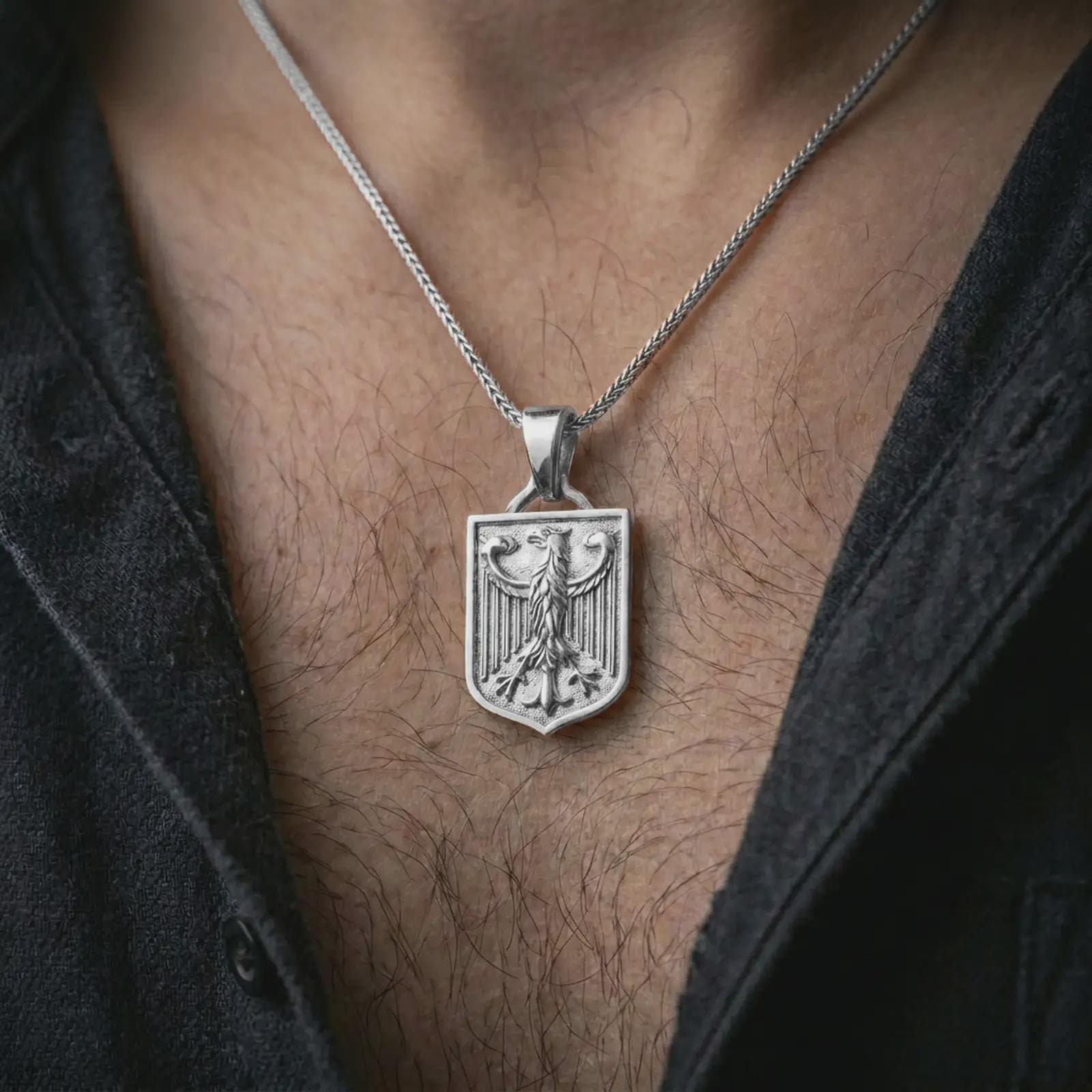Polished silver German eagle shield pendant necklace worn on the chest, masculine lifestyle shot highlighting the bright silver finish, shield shape, and sculpted eagle relief.