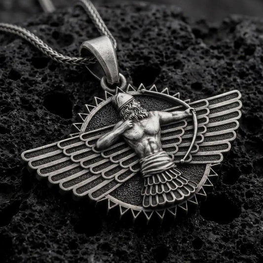An oxidized Faravahar pendant rests on dark volcanic rock in a macro studio close-up, showing a detailed winged Persian symbol with a central figure.