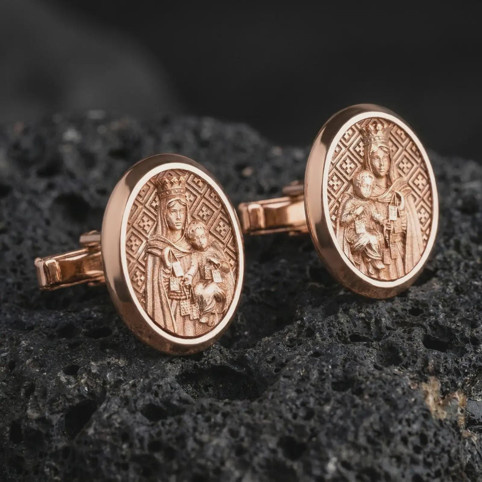 Rose gold plated Blessed Mother cufflinks are photographed on porous volcanic rock in a close-up studio composition with refined luxury lighting and religious detail.