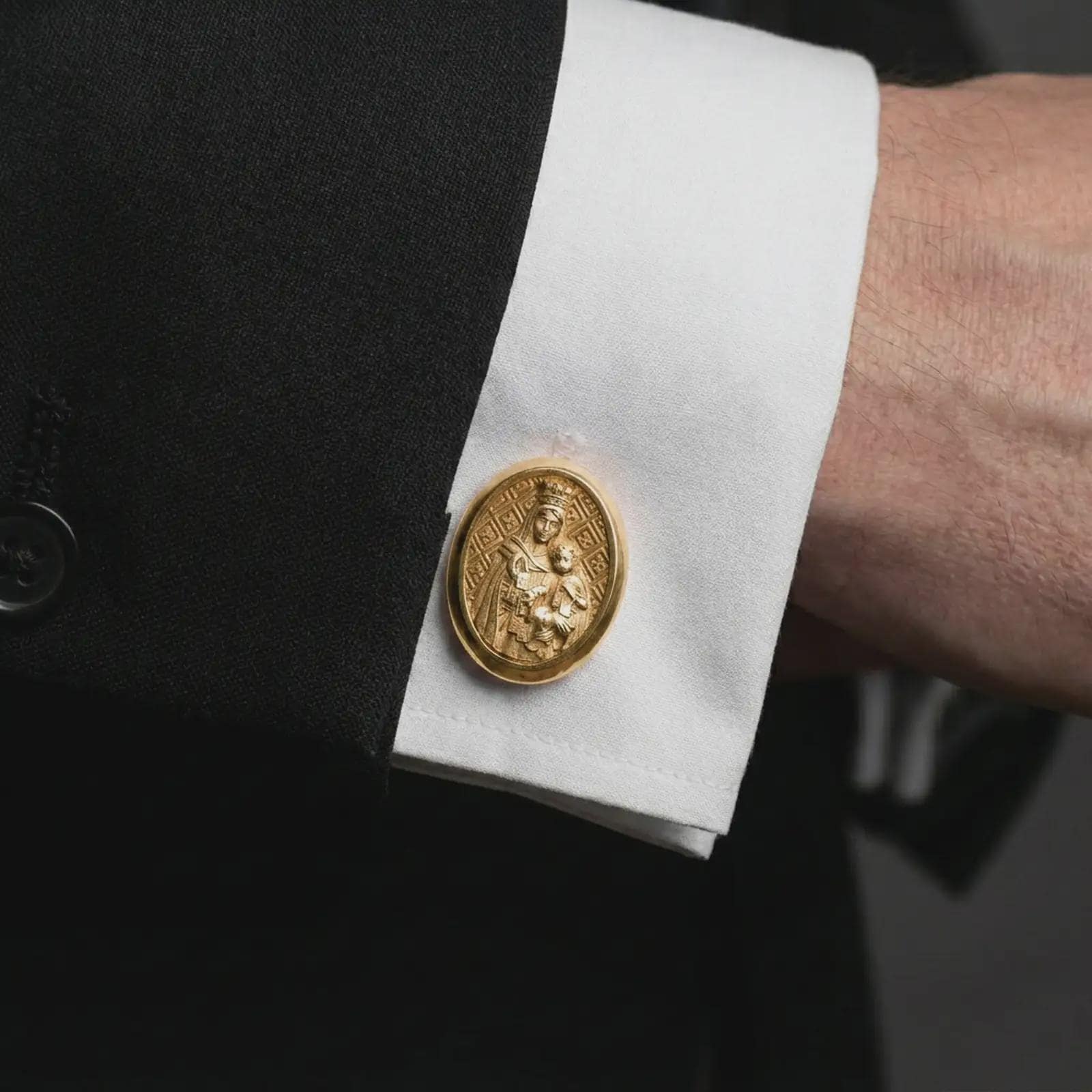 A gold plated Blessed Mother cufflink is worn on a white cuff in a close-up lifestyle shot, styled as a thoughtful religious gift for men.